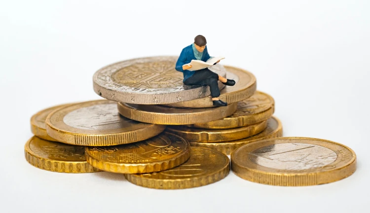 Figurka muže sedícího na mincích