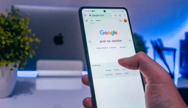 Ruka držící mobil s otevřeným vyhledávačem Google