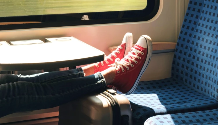 Cestující s nohama na kufru ve vlaku